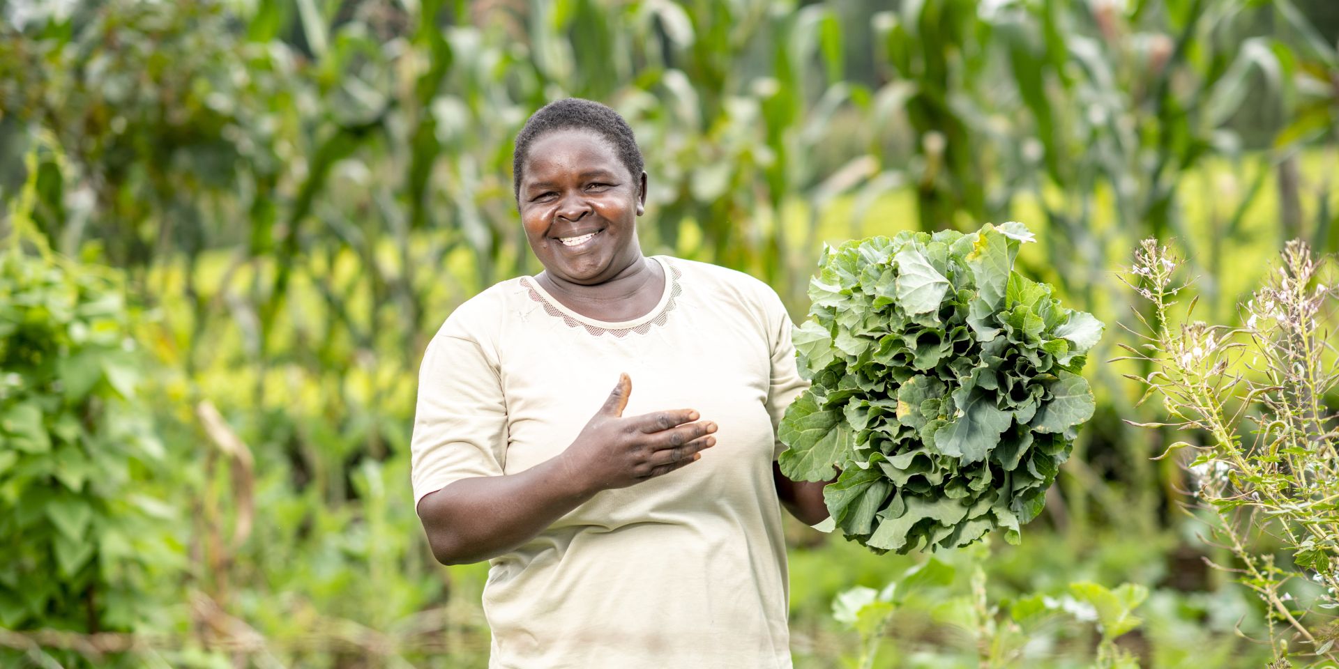 A farmer from Kapsabet, Kenya, stands holding a cabbage she's just harvested