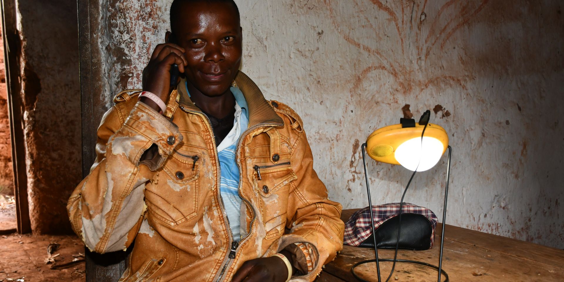  Angelo Hafashimana a farmer in Burundi sits with a phone a solar light he purchased from One Acre Fund