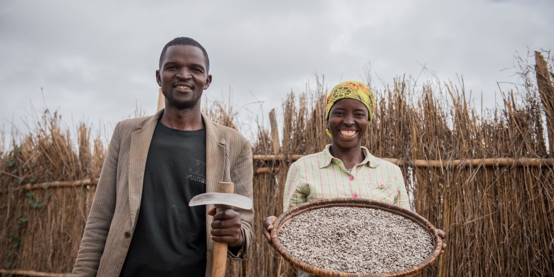 A couple stands together showing their sunflower seeds harvest