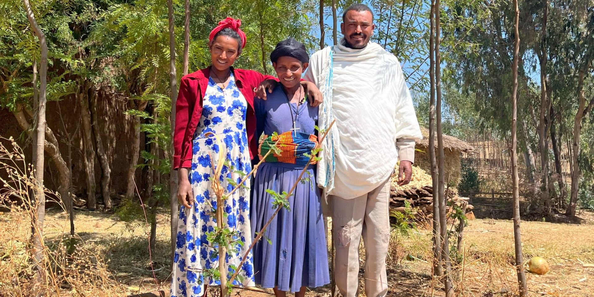 An Ethiopian tree farmer stands with his family in front of the trees he has grown. 