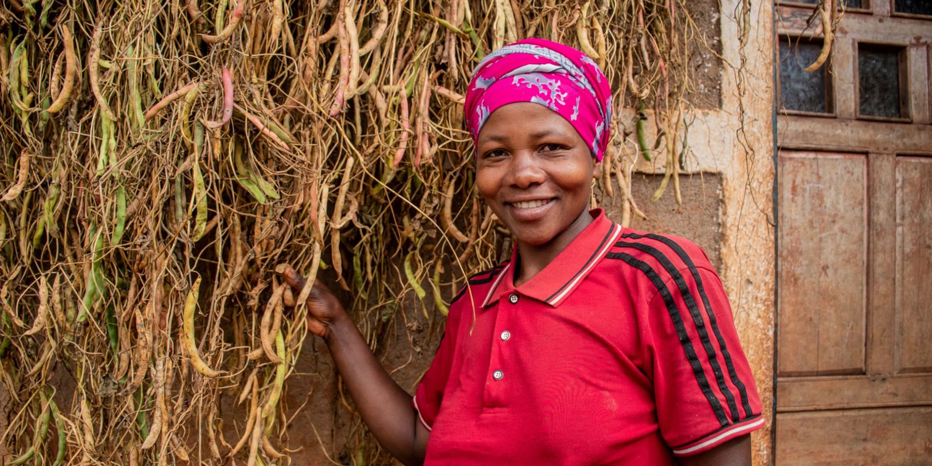 A smiling smallholder farmer showing her bean harvest
