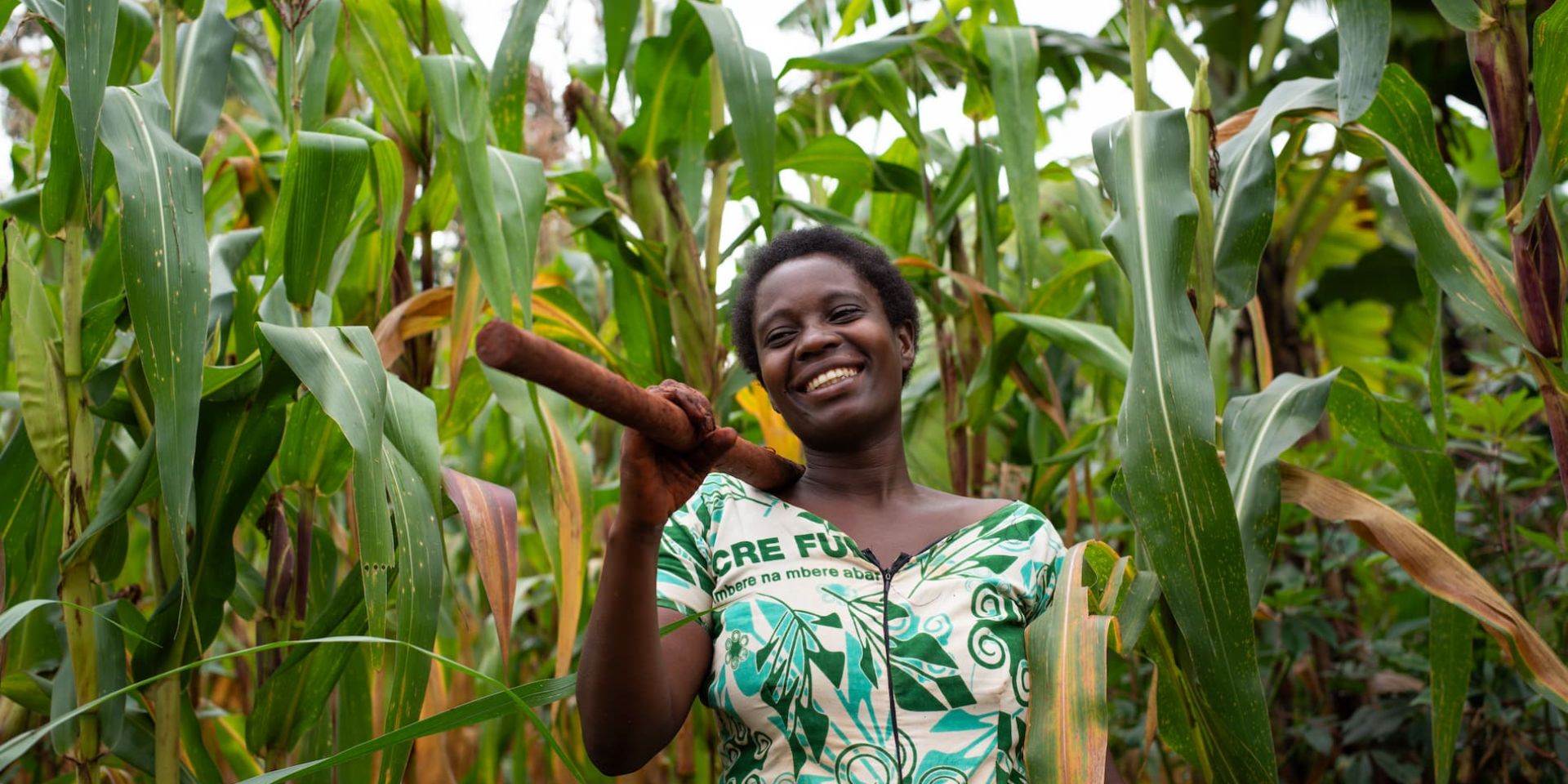 Asterie Ntahonvukiye, a farmer in Burundi, stands smiling in her maize field