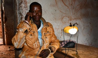  Angelo Hafashimana a farmer in Burundi sits with a phone a solar light he purchased from One Acre Fund