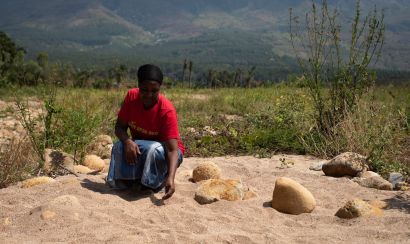 A Malawian farmer sits in her field which is now covered in sand thanks to Cyclone Ana