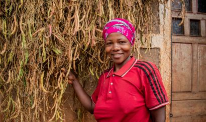 A smiling smallholder farmer showing her bean harvest
