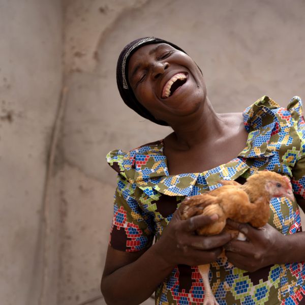 A farmer laughs as she holds her new chicken