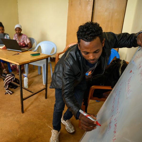 A One Acre Fund staff member in Ethiopia writes on a whiteboard while he leads a workshop