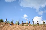 Farmers in Rwanda stand in a line tilling the soil