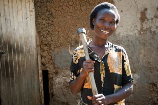 A farmer in Kenya stands holding her jembe