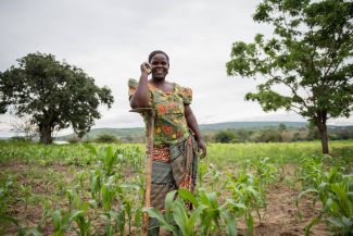 A woman farmer posing in her field full of crops