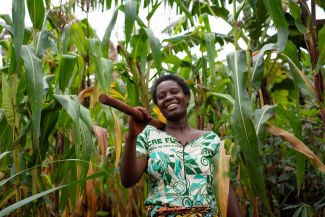 Asterie Ntahonvukiye, a farmer in Burundi, stands smiling in her maize field