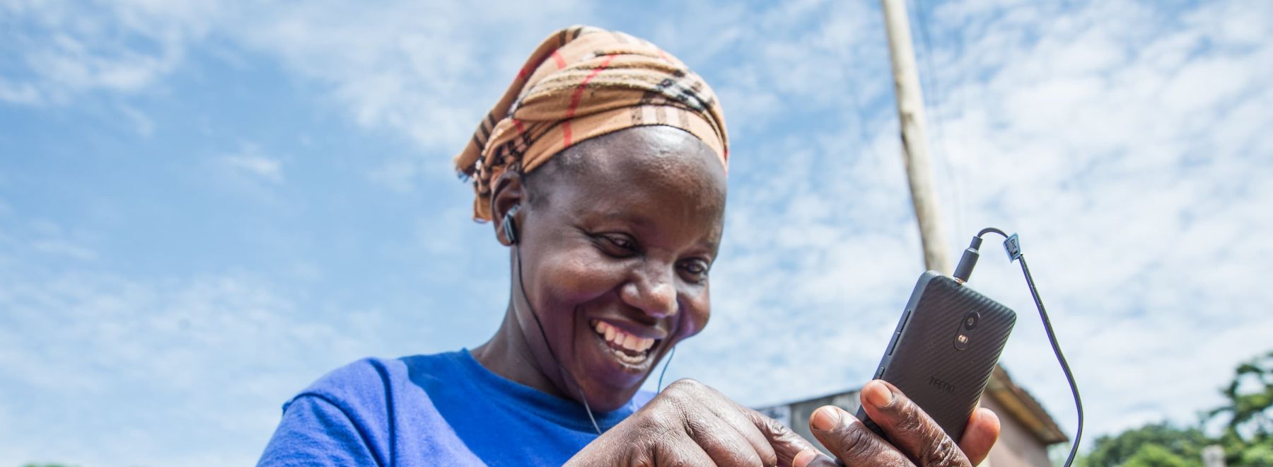 A farmer in Kenya using her new phone and earphones