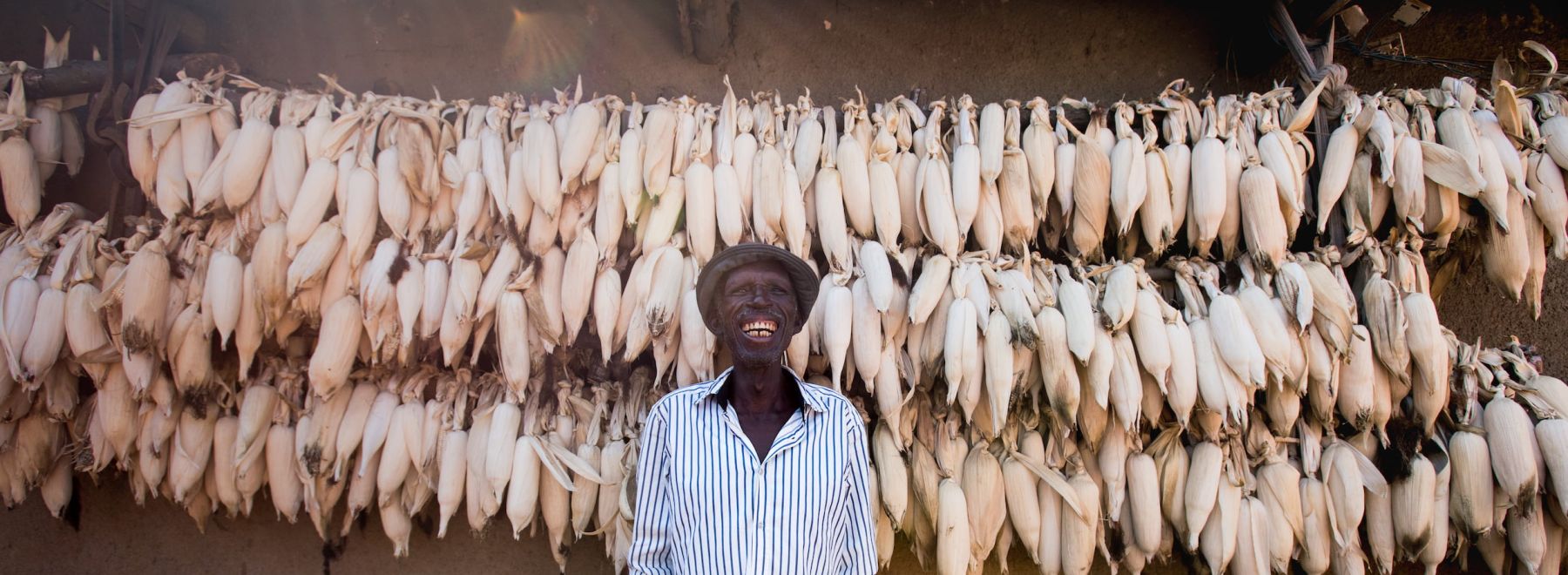 A farmers stands proudly in front of his drying maize harvest