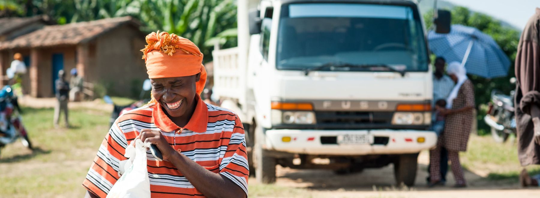 A farmer in Rwanda laughs as she receives her input delivery