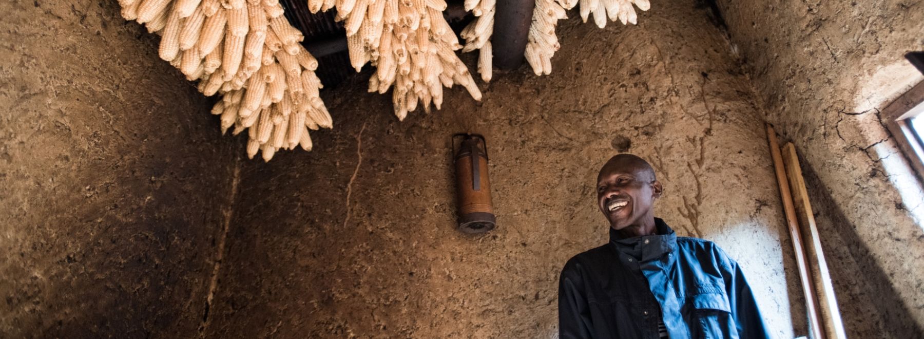 A Rwandan farmer with his maize hanging to dry