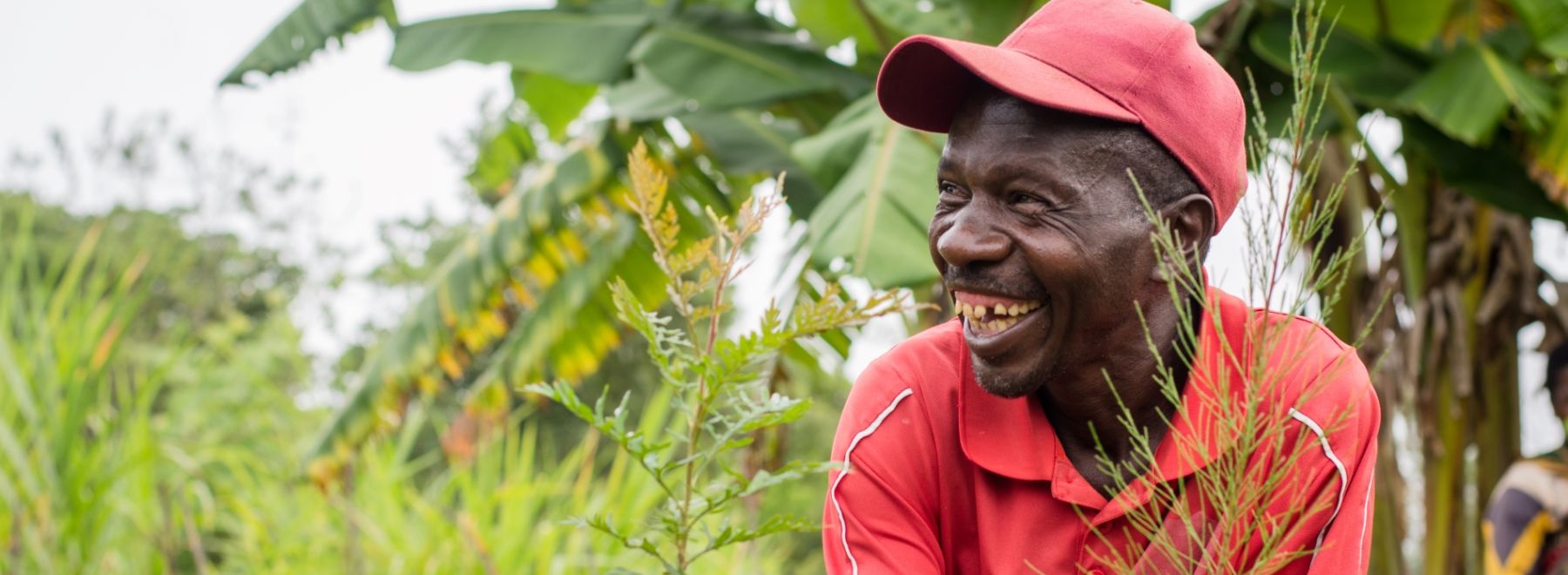 A farmer in Tanzania smiles as he holds his new tree seedlings
