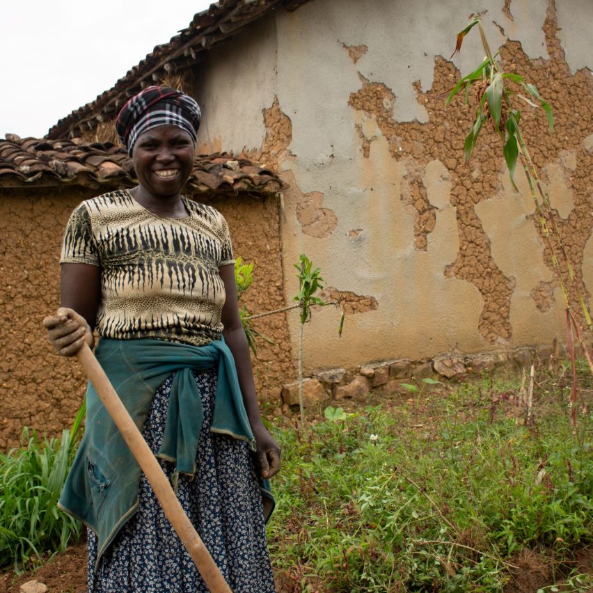 A smiling woman farmer stands proudly in her field