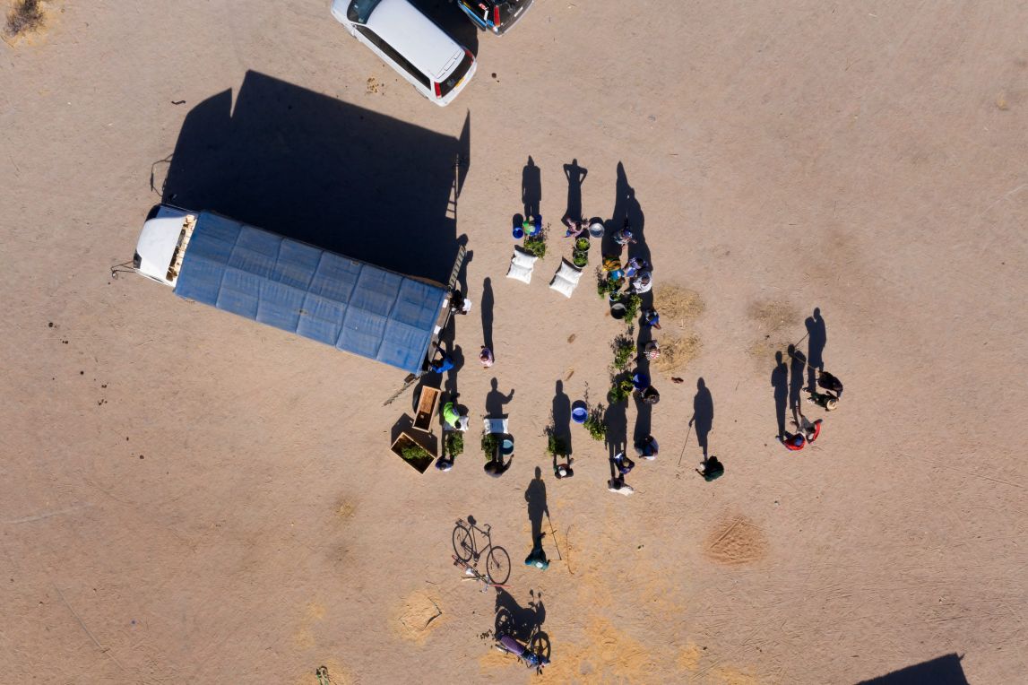 Aerial shot of farmers standing around a truck waiting for the delivery to be unloaded in a remote location