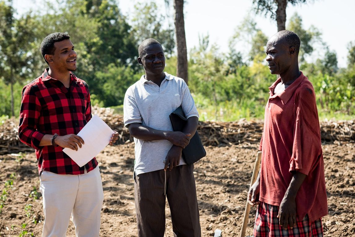 Daniel Omondi, an FO, and client discuss a seed planting trial in Kenya