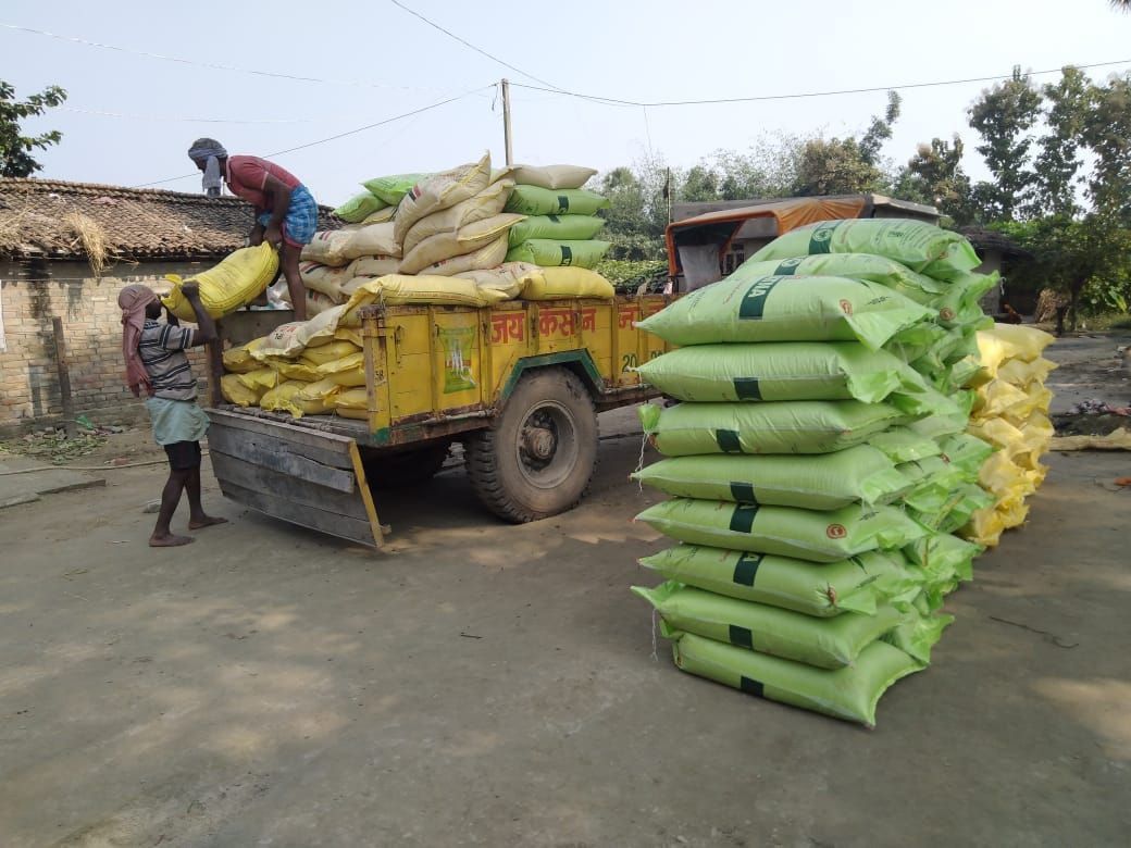 People loading bags of farm supplies onto a truck
