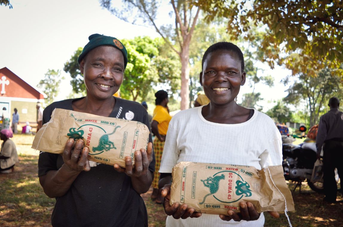 Two women farmers holding bags of seed