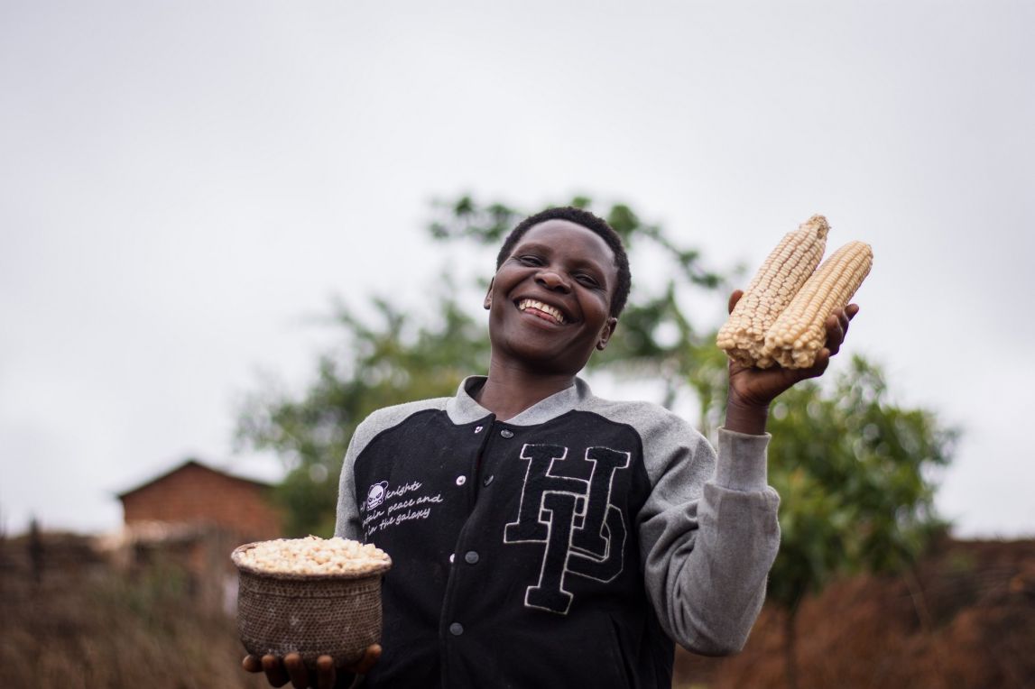 Upendo Mgaya, one of the farmers we serve in Njombe, Tanzania, poses with some of her maize harvest.