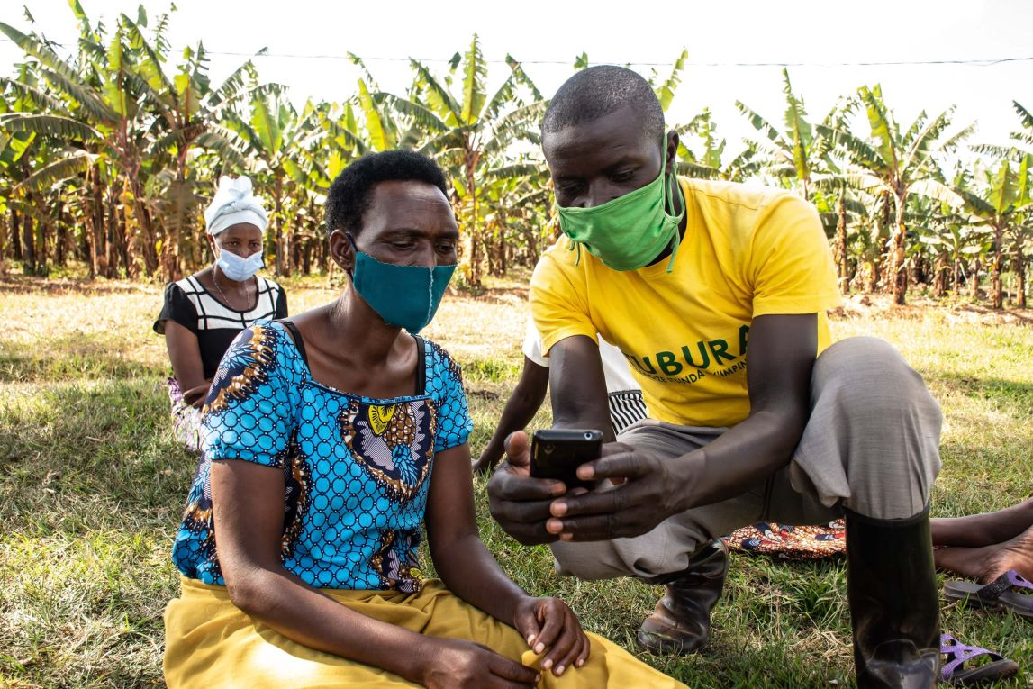 Field Officer helps Rwandan farmer enrol using their mobile phone.