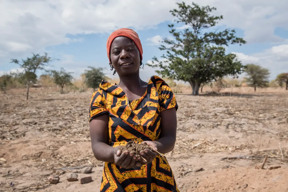 Farmer in open field cups soil in her hand