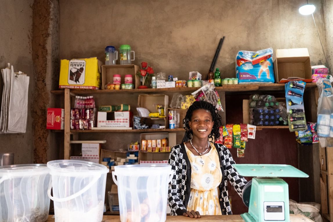 Alphonsine Musanabera is a 24-year-old farmer from Rwimbogo cell, Rwamagana district. She grows beans, maize, groundnuts,s and fruits. She has been farming with One Acre Fund since 2020. Since joining her harvest has increased and sold surplus hwich helped her invest in her shop business. She also baught a solar lamp from One Acre Fund, which is helping her to light her shop when it is dark.